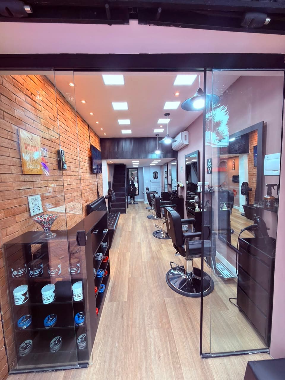 Interior da Barbearia Luma da Rua Tupis: parede de tijolinho, cadeiras de barbeiro e vitrine de produtos